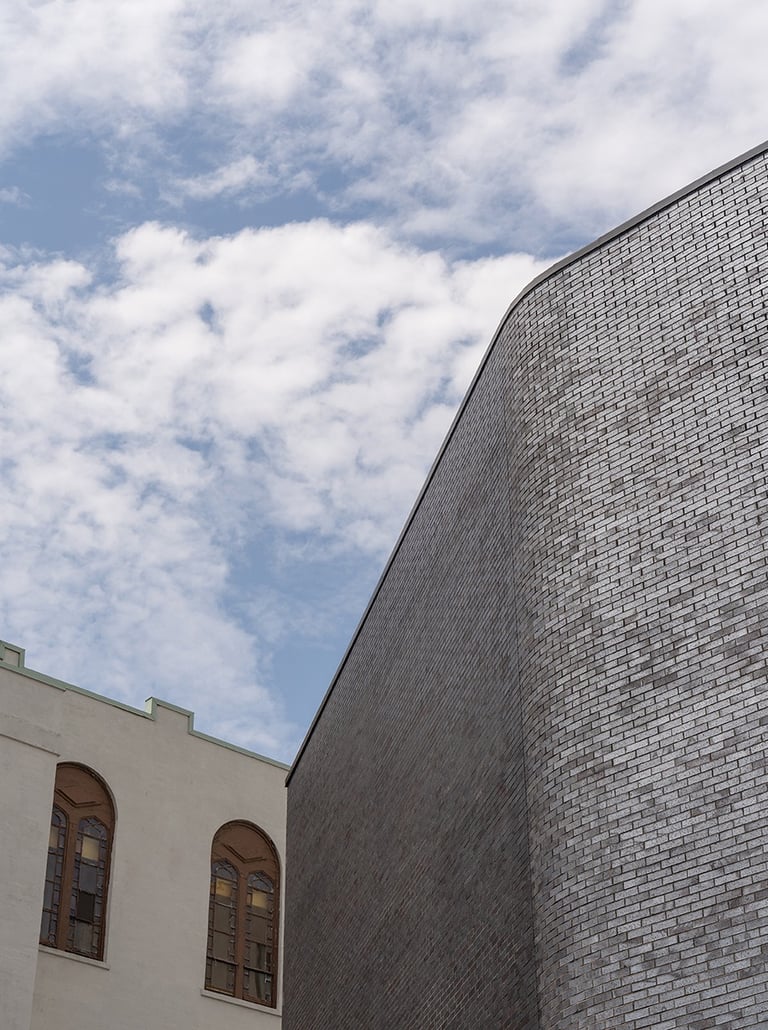 a brick clad building next to a white heritage building