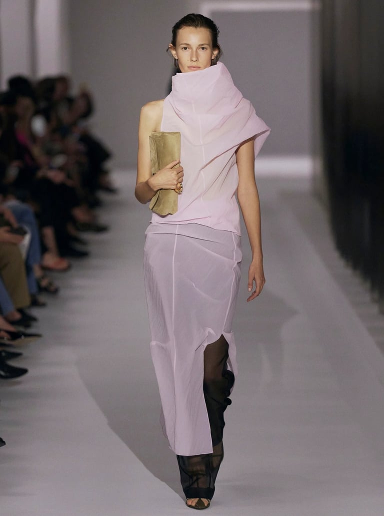 Model in a pastel draped gown with sheer layers on the Khaite runway.