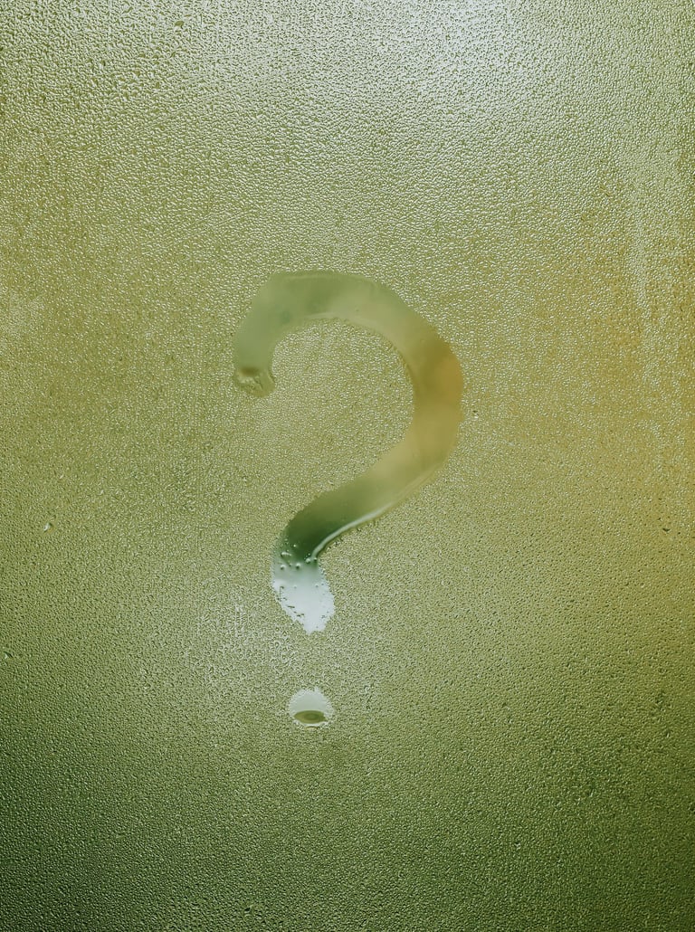 A question mark drawn in condensation on wet glass