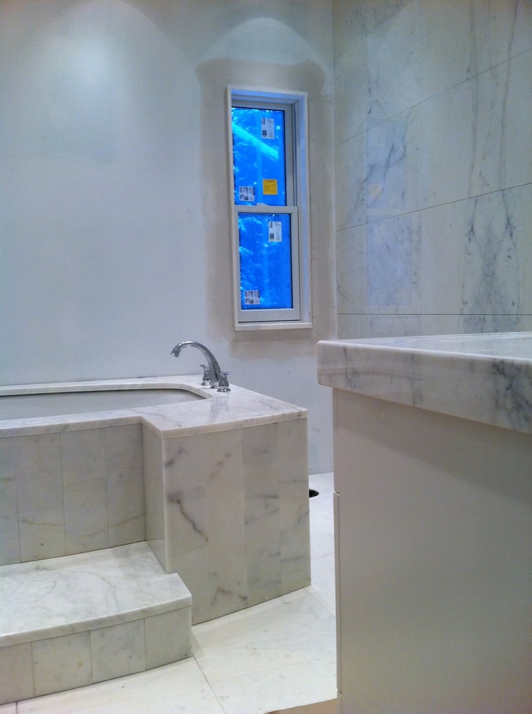 Modern luxury bathroom under construction with white marble tile bathtub and matching vanity.