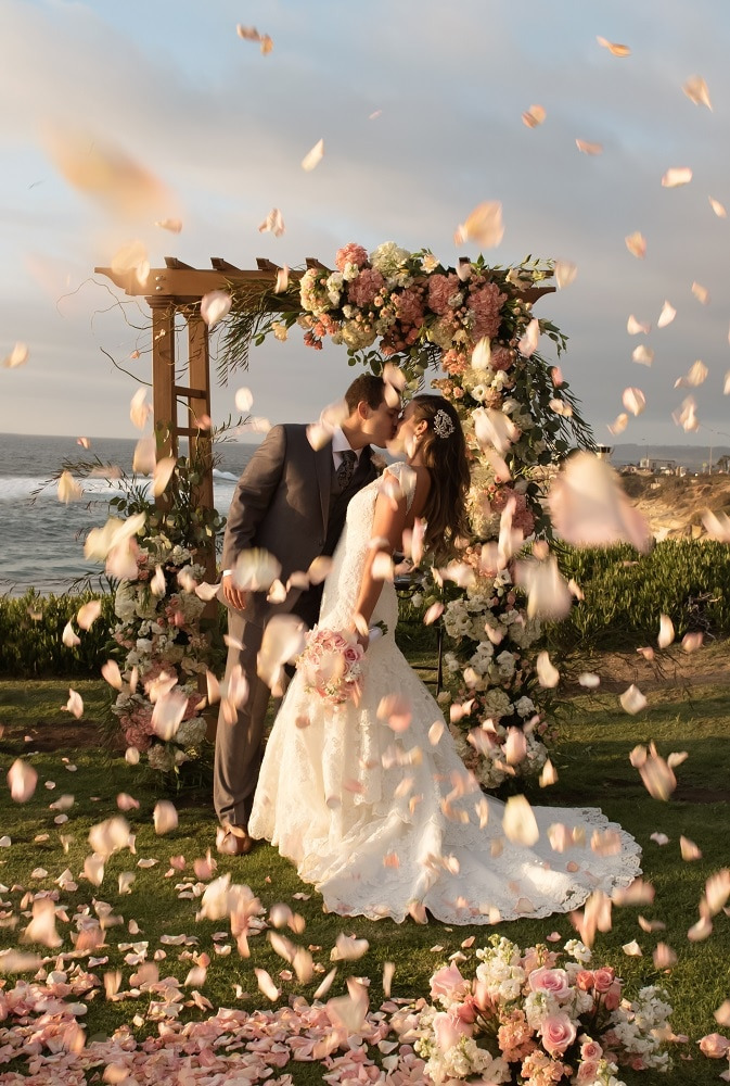 couple kissing under floral decorated arbor at cuvier park la jolla