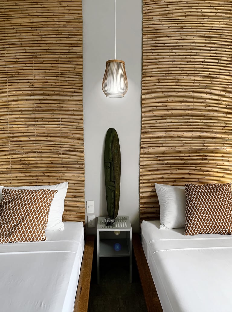 a couple of beds in a room with a lamp