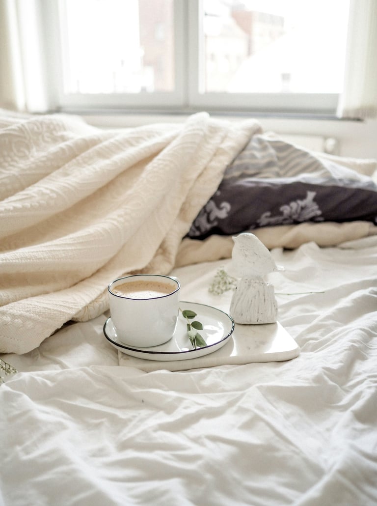 a cup of coffee and a tray on a bed