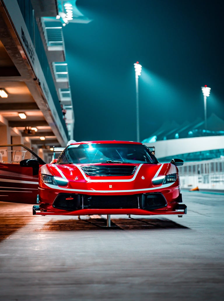 Red Ferrari racing car on a race track at night under bright stadium lights.