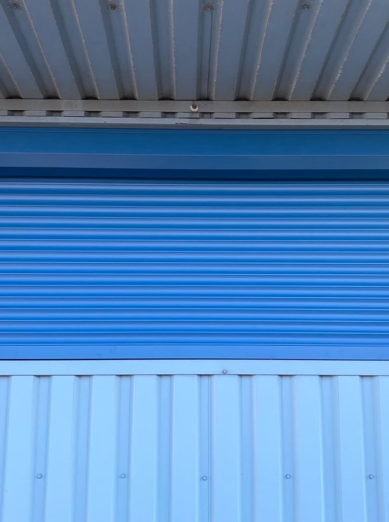 šiame paveikslėlyje matomos apsauginės žaliuzės mėlynos spalvos sumontuotos ant lango