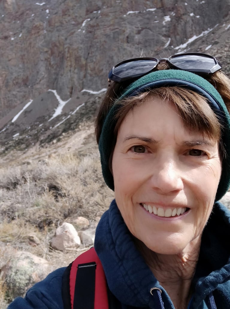 Susan Rensberger in the rugged Andes mountains wearing a headband and sunglasses on her head