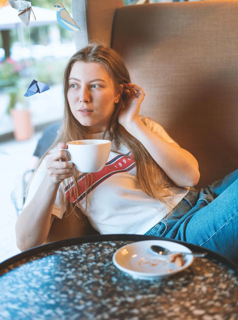 90s style portait picture of a young girl in a coffee shop drinking coffee in a big armchair  