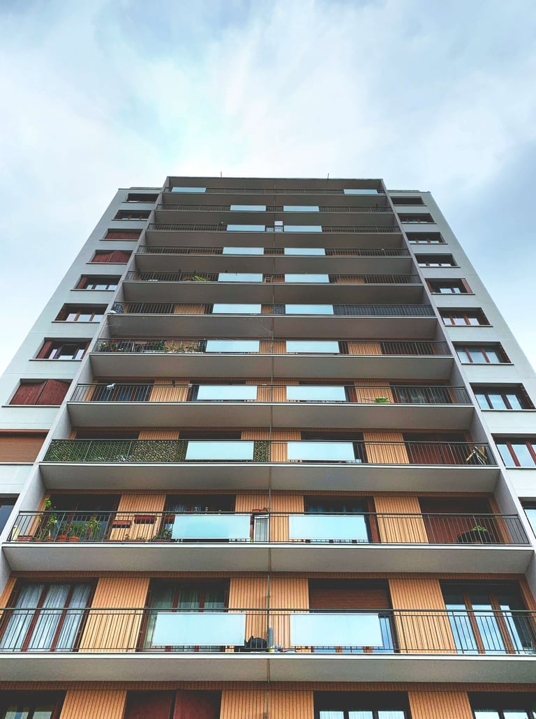Low angle view of a modern apartment building with glass balconies and wooden facade panels.
