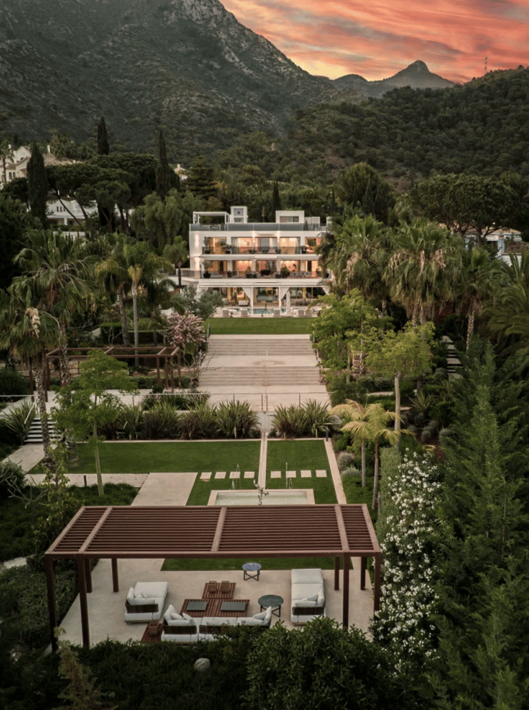 Aerial view of a modern white villa in a mountain valley at sunset