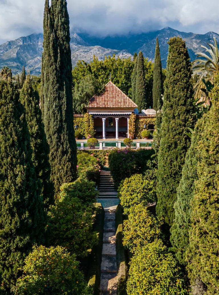 Cypress-lined pathway leading to pool pavilion with mountain backdrop