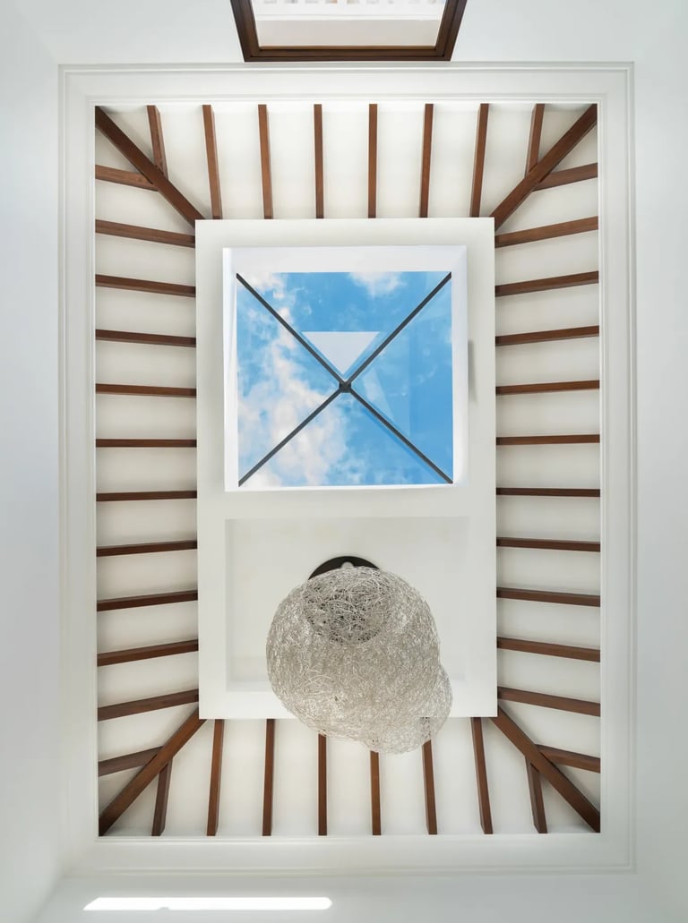 Atrium skylight with exposed wooden beams and contemporary chandelier