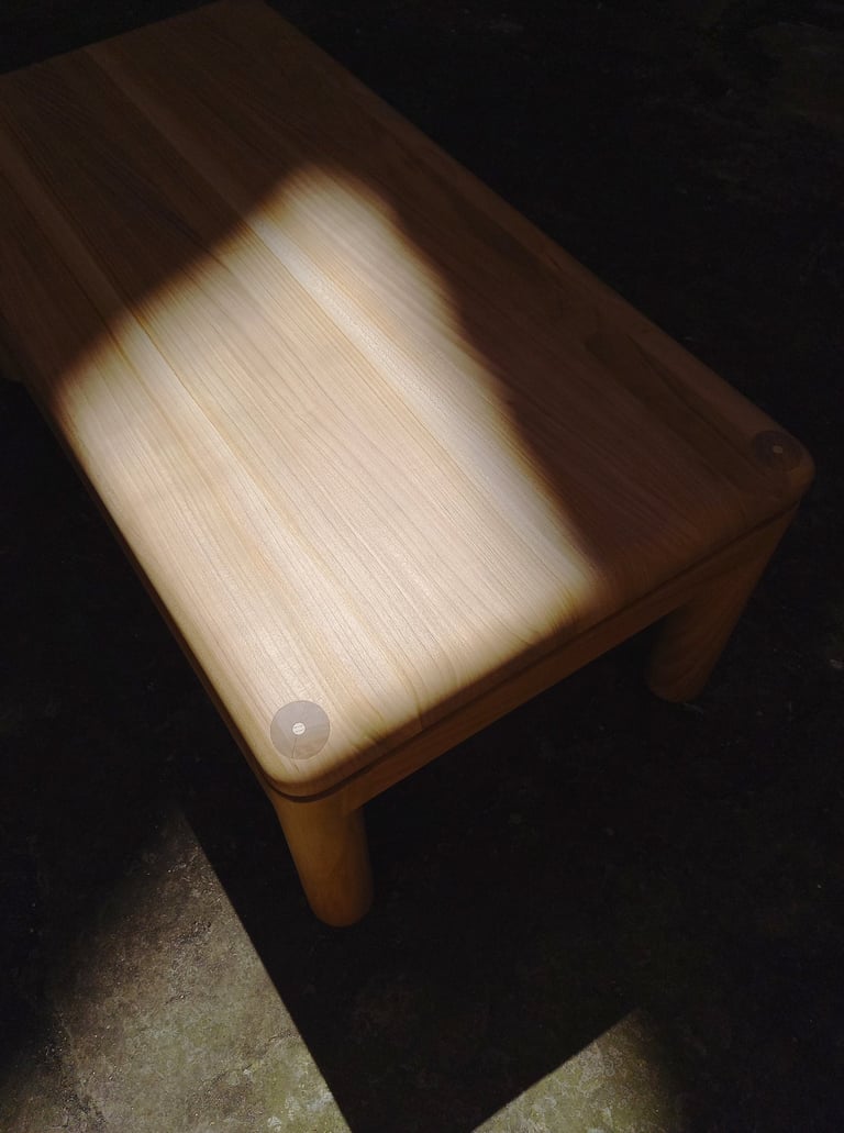 table basse en merisier aux angles et arêtes arrondis dans un rayon de soleil