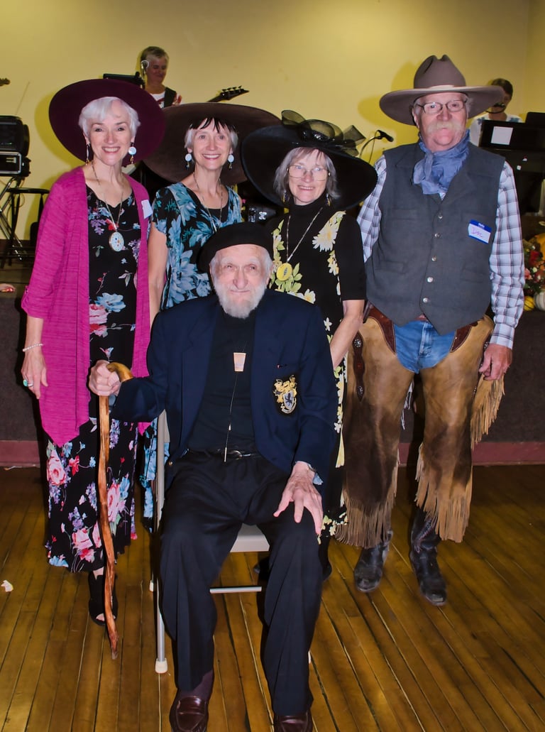 four people wearing hats standing behind an old man for family group picture
