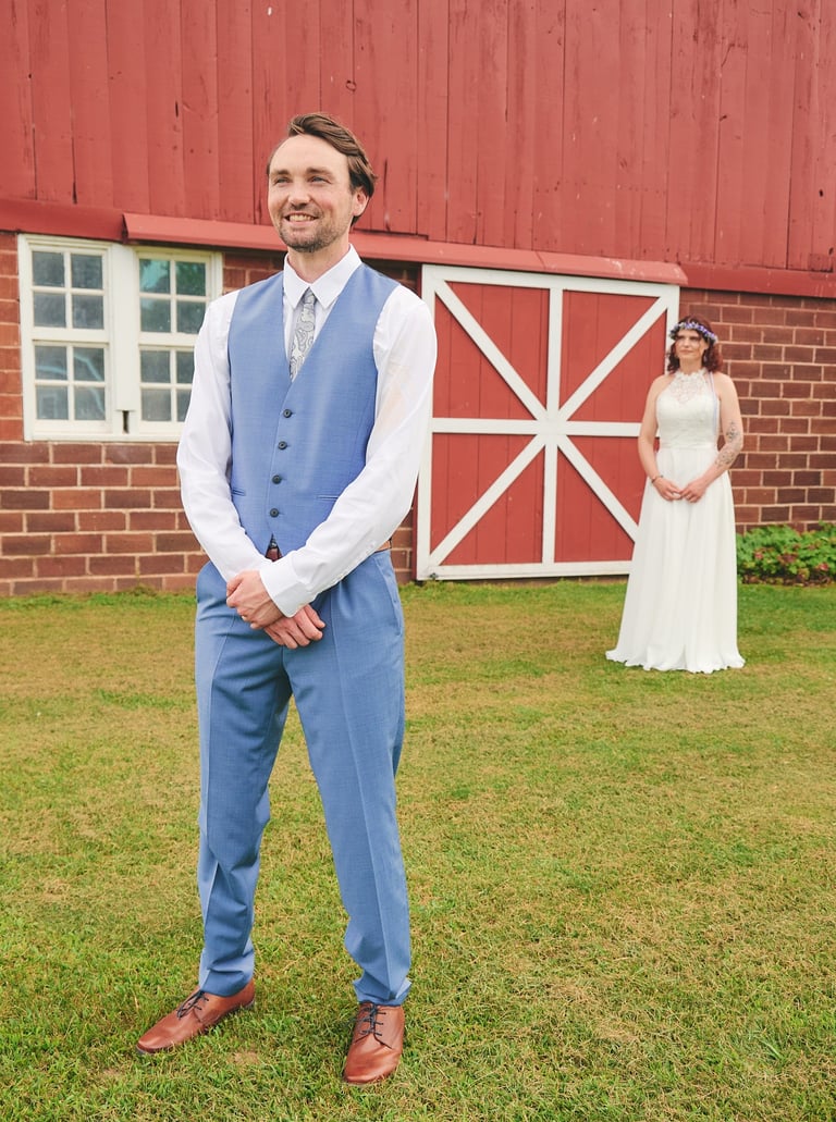 a man in a blue vest and suit and a woman in a white dress behind him