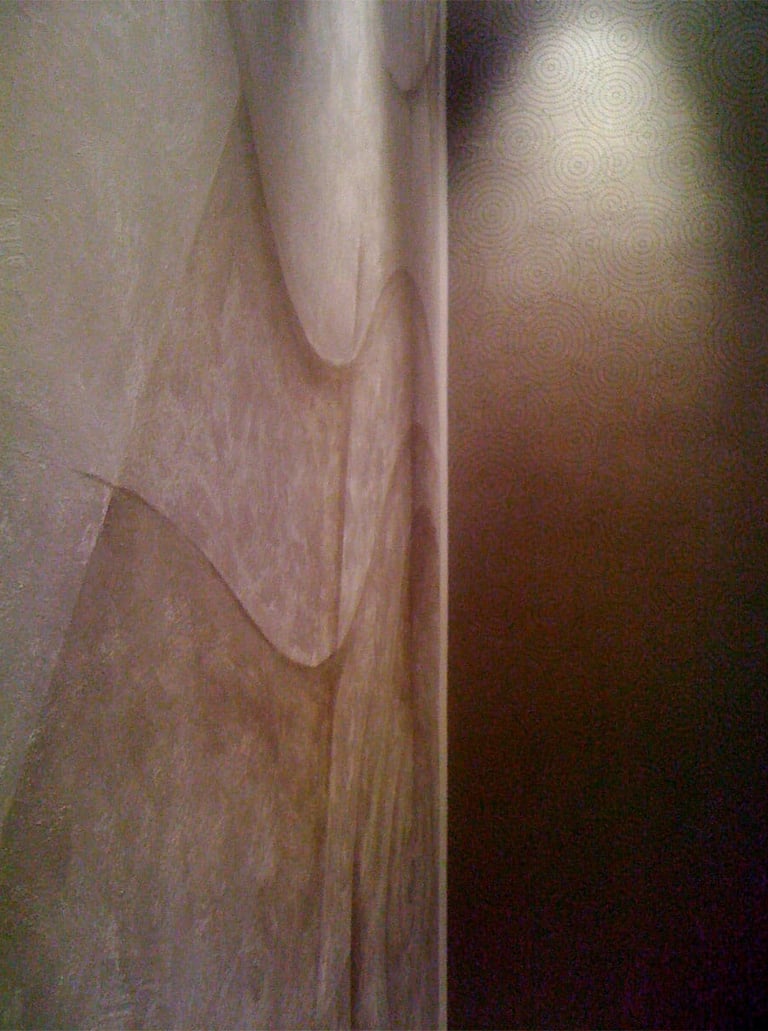 Dimly lit large silver mural with wavy lines in an elegant office.