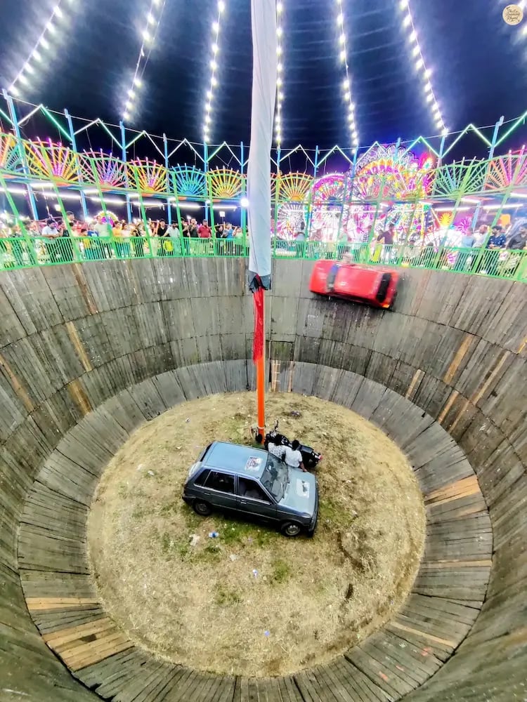 Thrilling Maut ka Kuaan act with cars speeding on vertical walls at Kota Dussehra Mela.
