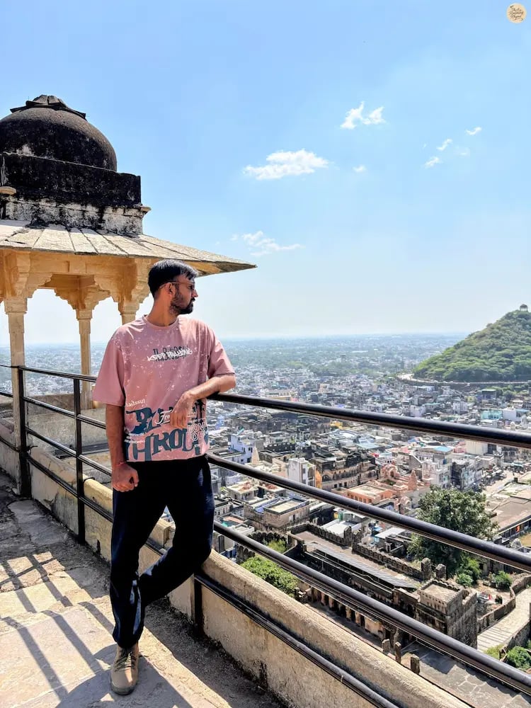 Traveler overlooking the blue city of Bundi from Garh Palace, capturing the panoramic view below.