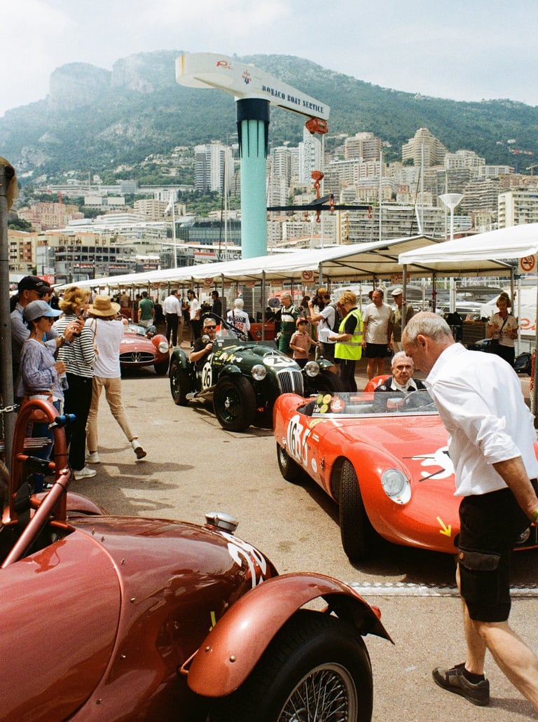 a man in a white shirt and black shorts is walking across of a group of race cars in the paddoc