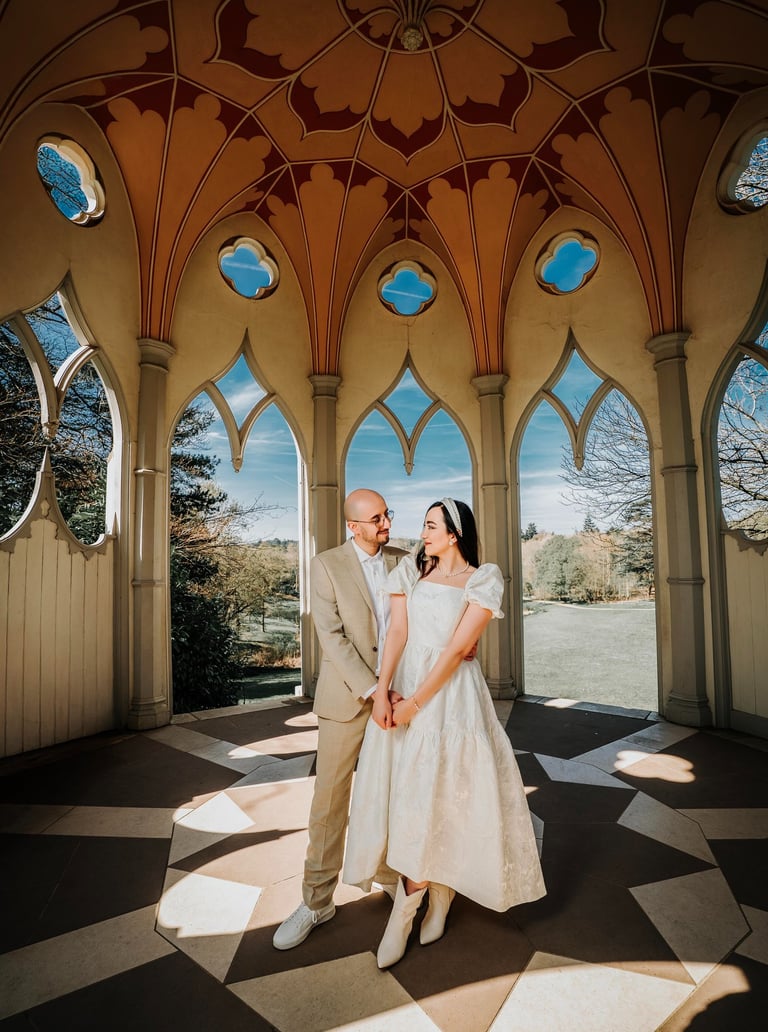 Couple holding hands inside an ornate pavilion in Painshill Park, captured by Fred Art Studio.