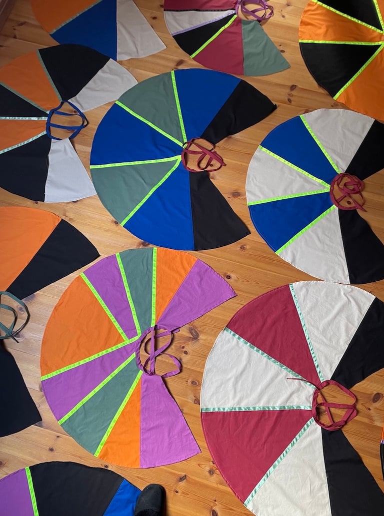 Handmade colorful circular capes with neon trim. 