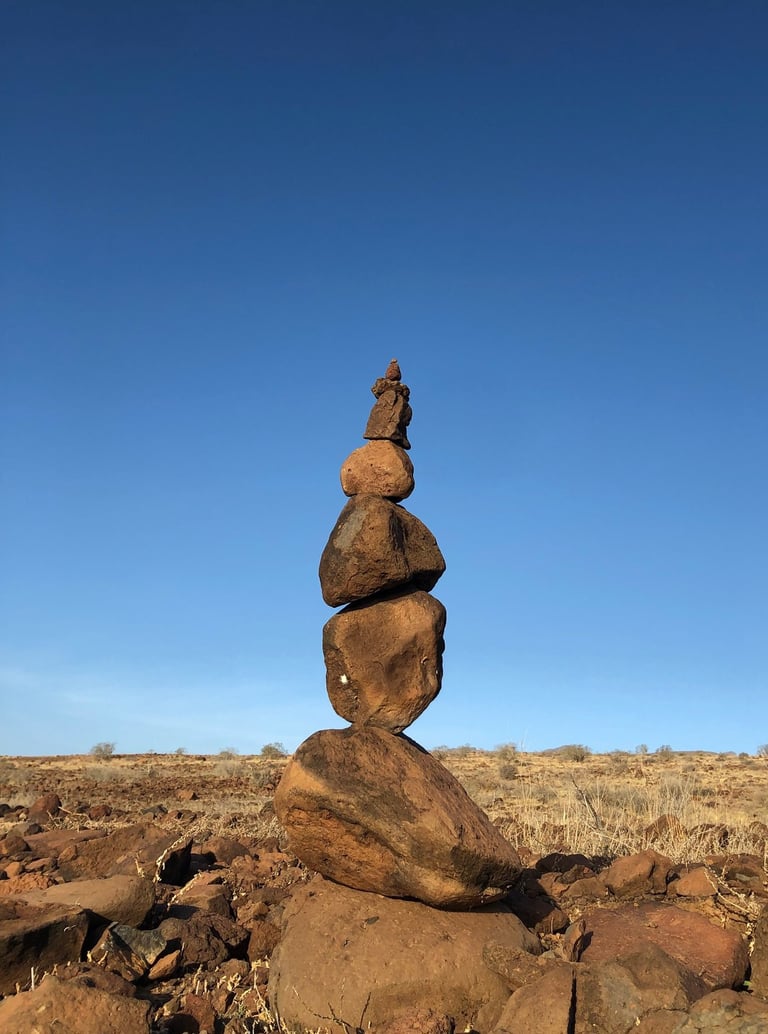 stacked stones on dry land against blue sky