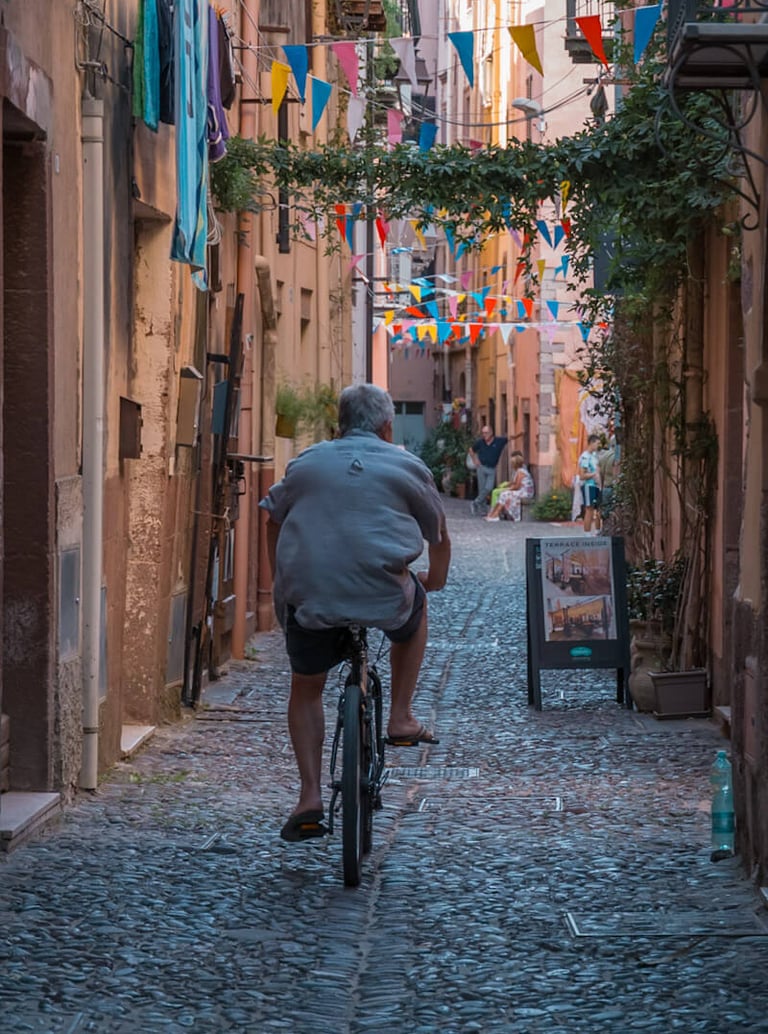 Man riding a bicycle in a cobblestone street in Bosa, Sardinia