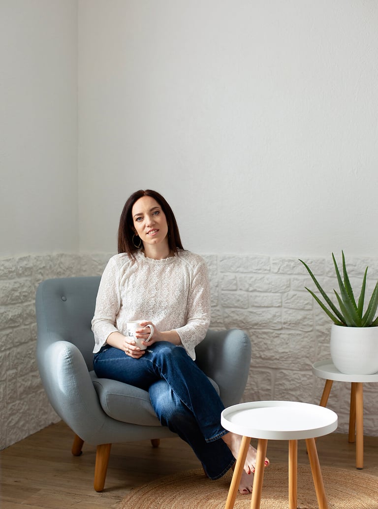 a woman sitting in a chair with a plant in front of her