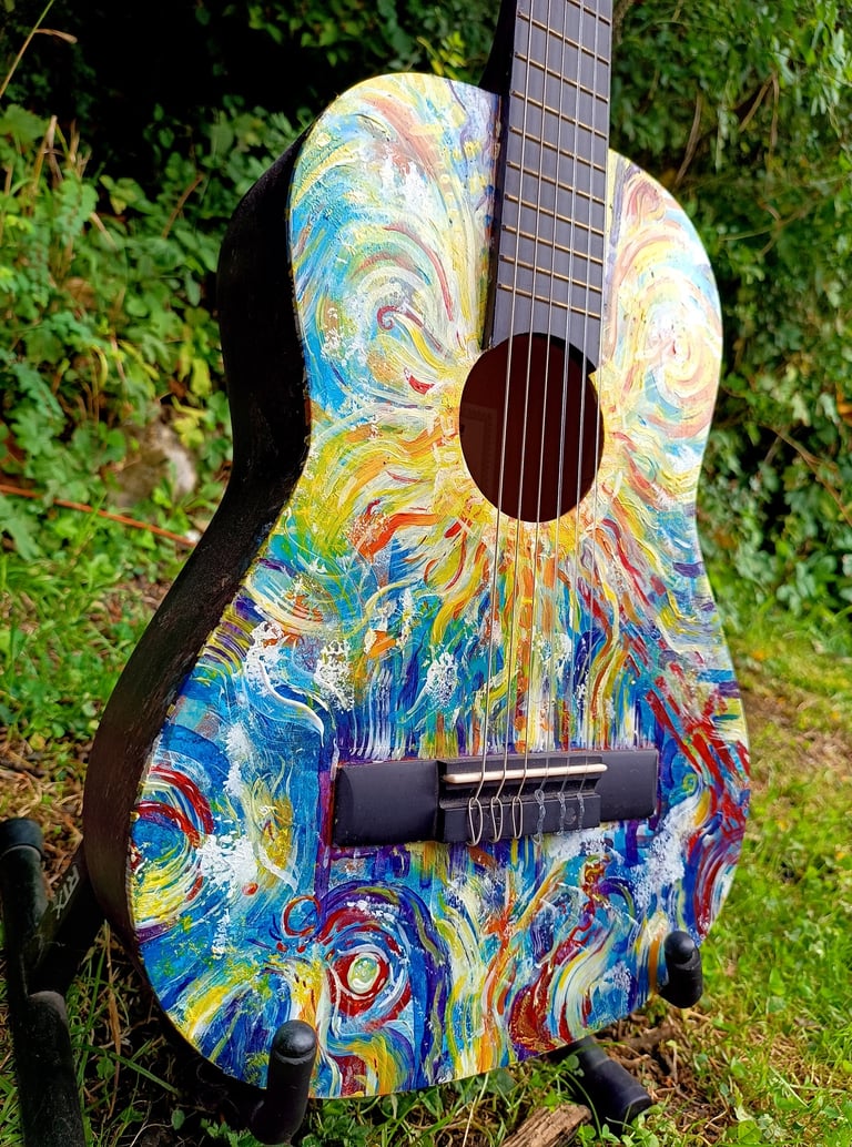 peinture sur guitare aux couleurs vives, avec un soleil autour de la rosace et des formes abstraites