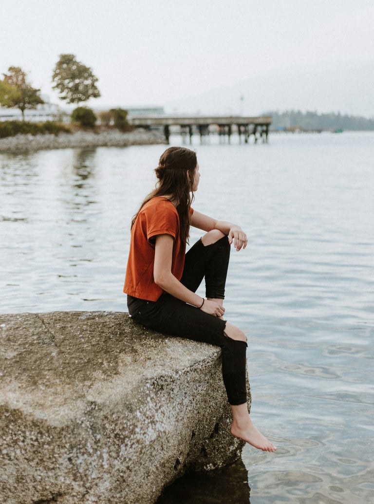 Jeune femme assise sur un rocher au bord d'un lac