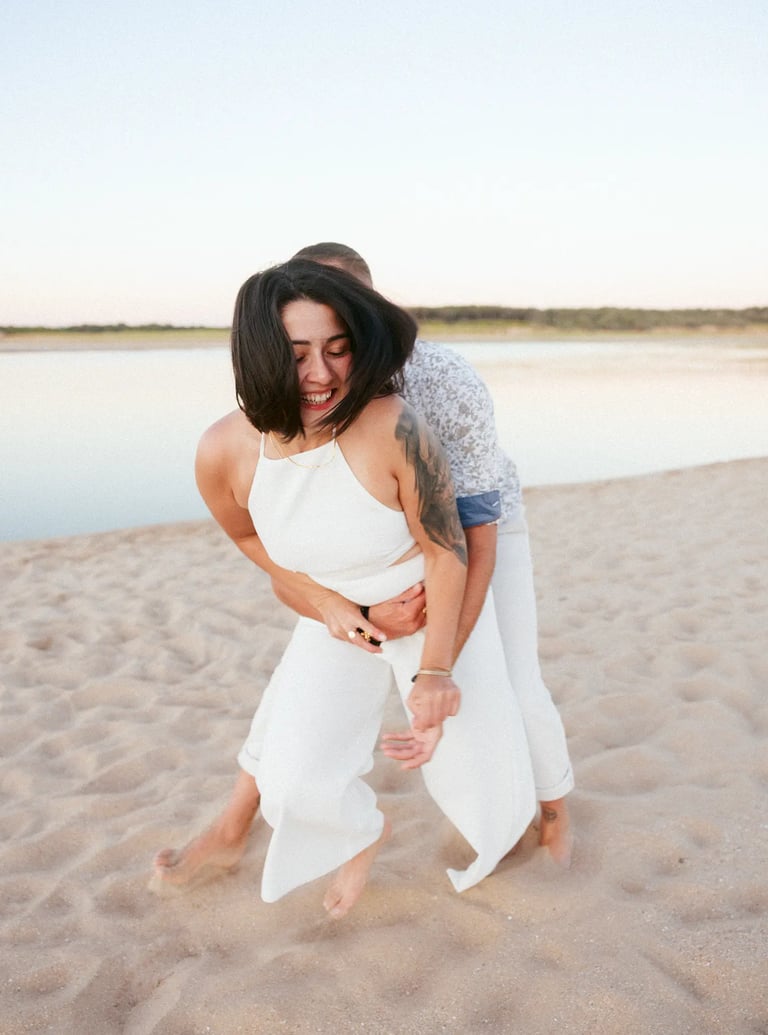 un couple s'amuse et joue lors d'un shooting couple sur des tons pastel plage du Veillon en Vendée