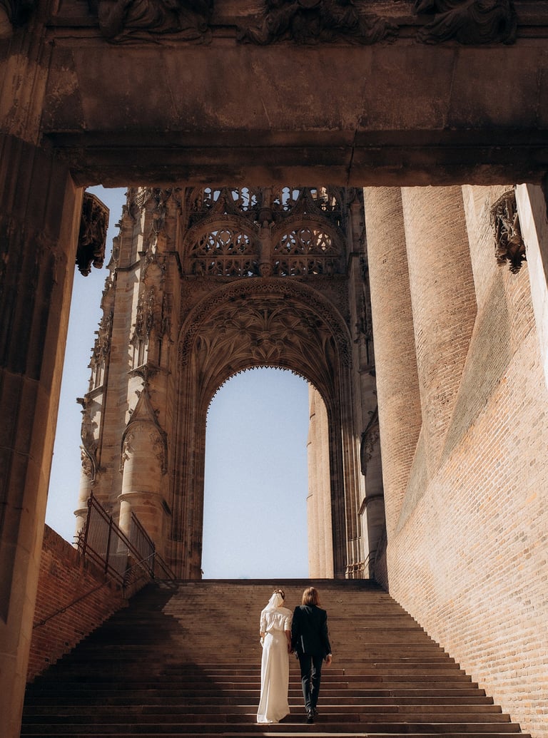 a bride and groom walking down stairs in a cathedral