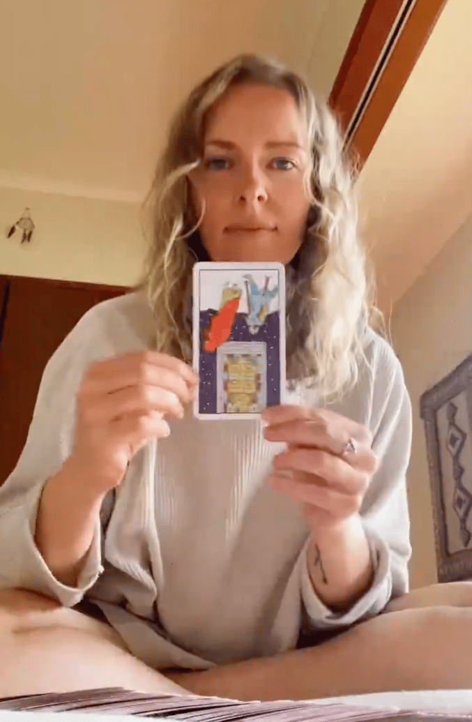 Natalie holding the Five of Pentacles reversed in a live tarot reading.
