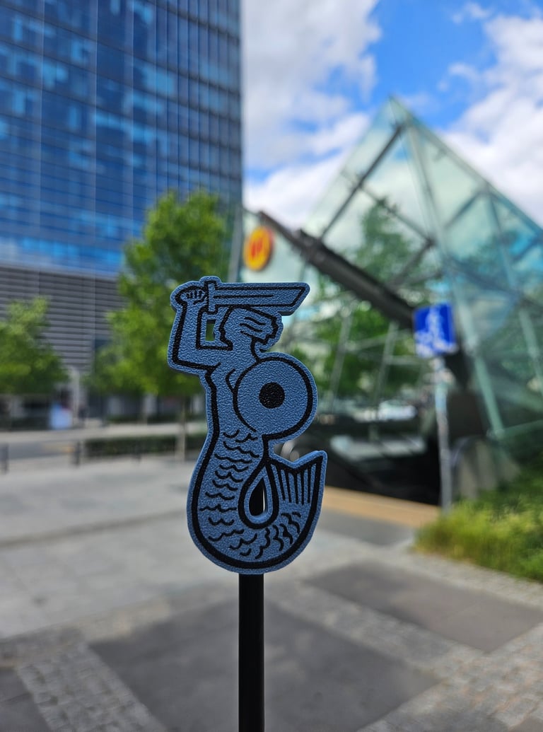 Niebieska syrenka na tle wejścia do Warszawskiego metra 