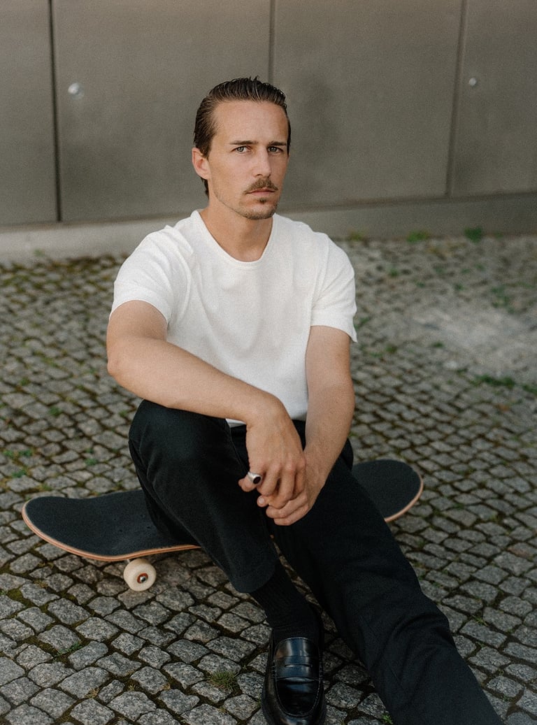 Portrait of artist and designer Philipp Schäfer sitting on a skateboard