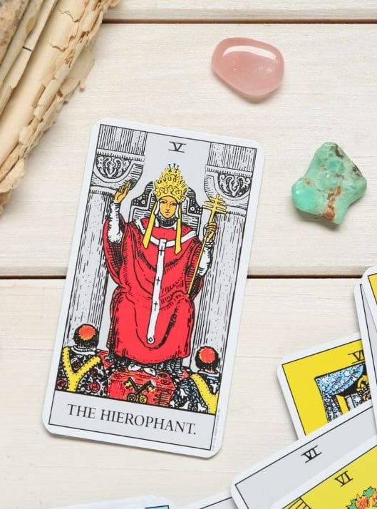 The Hierophant tarot card on a stack with crystals for tarot study for beginners