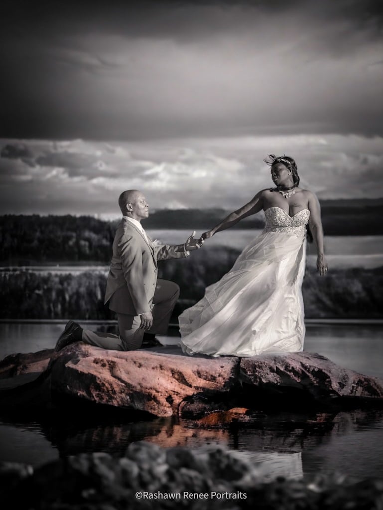 a bride and groom holding hands on a rock posing for wedding portraits
