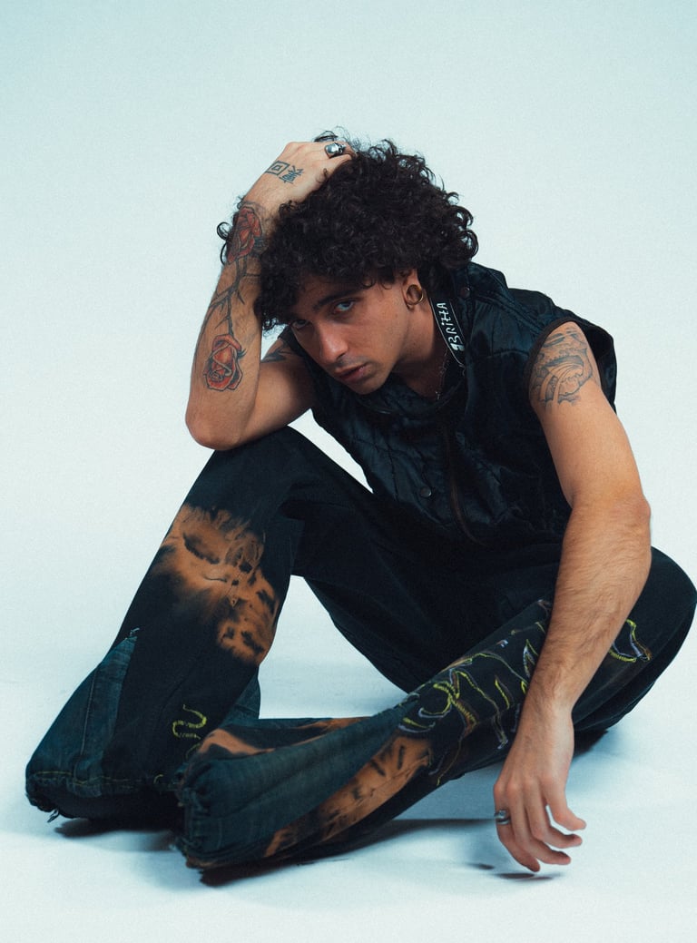 Klaus Noir su sfondo bianco seduto e con una mano in testa