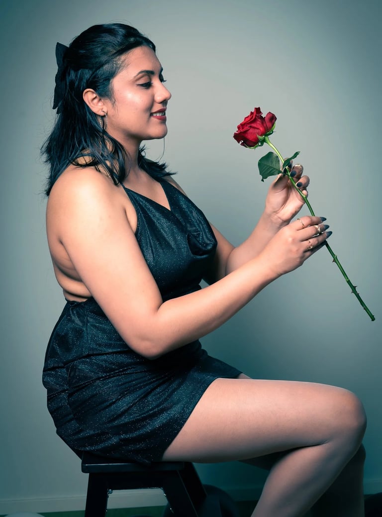 a woman in a black dress sitting on a stool
