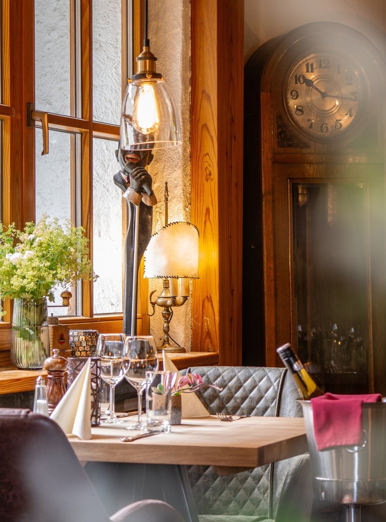 Eleganter Restauranttisch mit Weingläsern, antiker Standuhr und warmer Ambientebeleuchtung