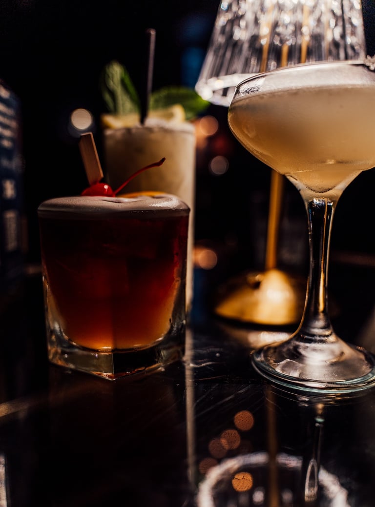 a table with a glass of alcohol and a cocktail