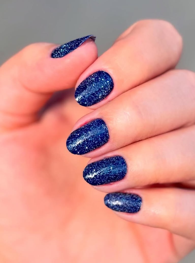 Esmaltação em gel azul marinho profundo com partículas de glitter prateado, apresentando brilho intenso e duradouro.