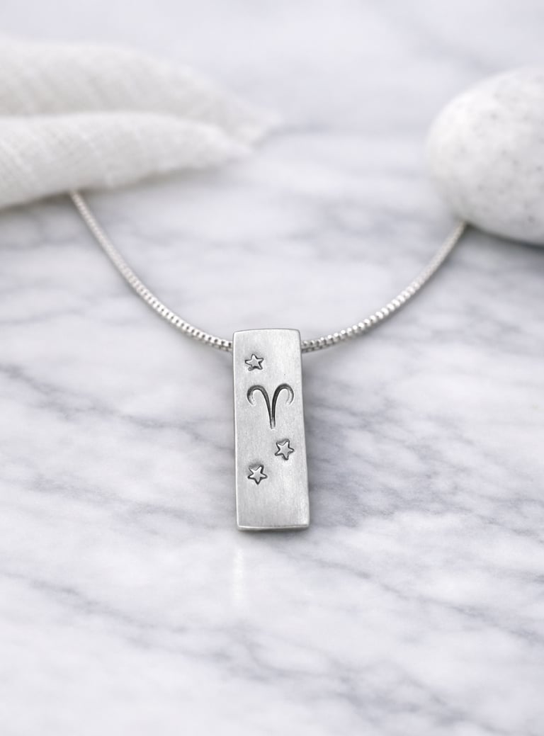 Handmade 999 silver Aries zodiac necklace with a vertical bar pendant on a marble surface.