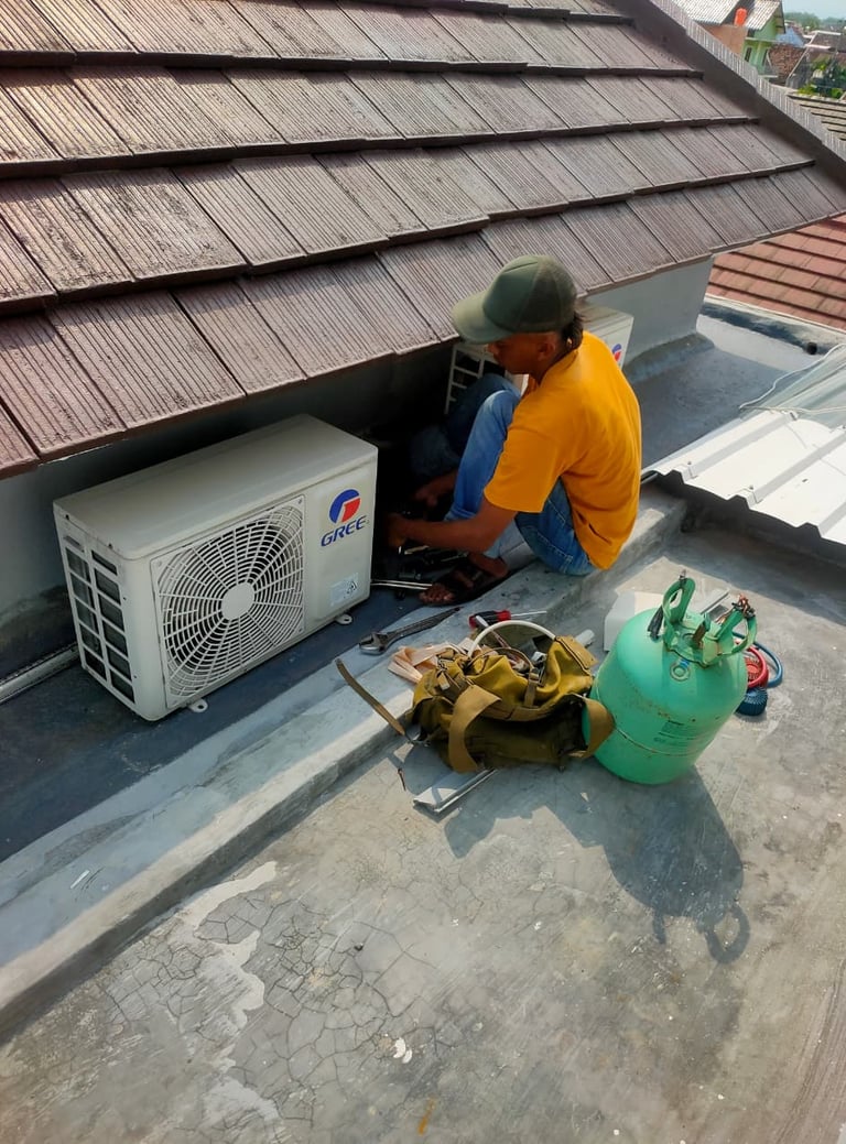 seorang teknisi service ac jogja sedang pengerjaan unit luar outdoor