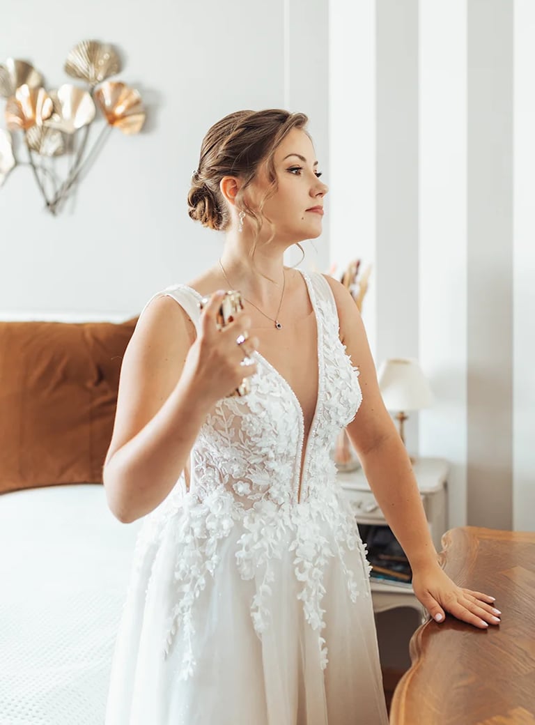 Mariée dans une belle robe qui se parfume durant ses préparatifs.