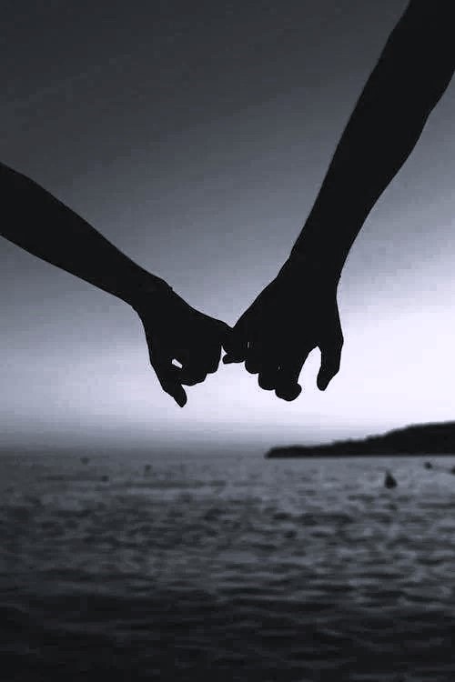 A couple holding hands in front of sea. The picture signifies it is time for pleasure on vacation