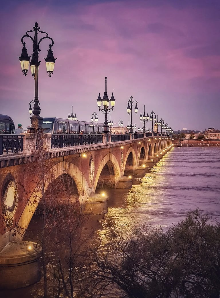 La nuit tombe sur le pont de pierre à Bordeaux et le ciel est rose