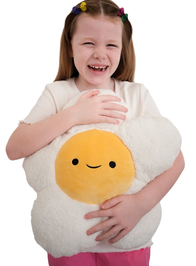 A smiling young girl holding a daisy-shaped plush