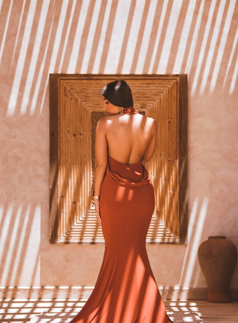 High-fashion portrait in Dakhla showing geometric shadow play on a resort wall with a model in an elegant backless dress.