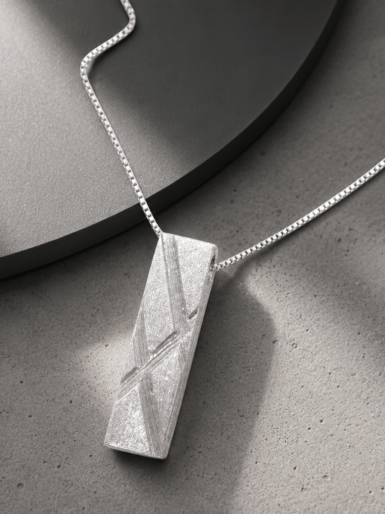 Handcrafted modern 999 fine silver pendant necklace displayed on a white marble surface.