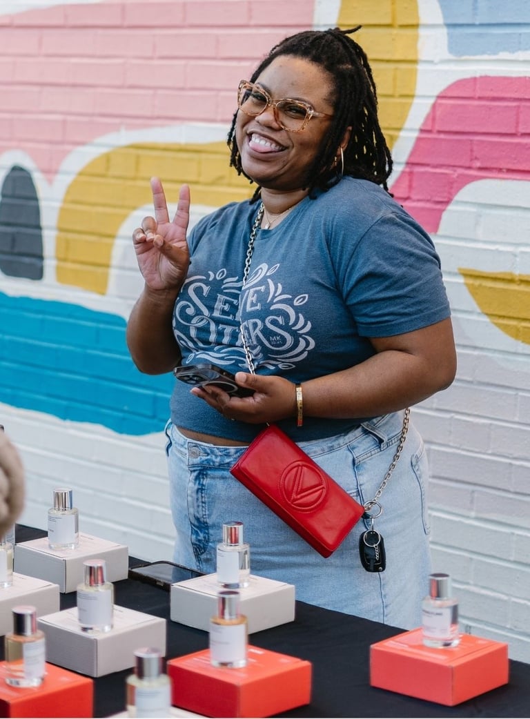 a woman standing in front of a table with a lot of perfumes